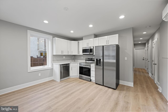 kitchen featuring appliances with stainless steel finishes, light hardwood / wood-style floors, white cabinetry, and sink