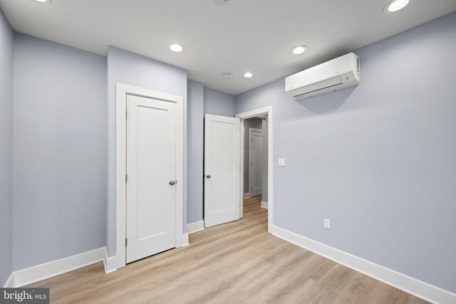 unfurnished bedroom featuring light hardwood / wood-style floors and a wall mounted air conditioner