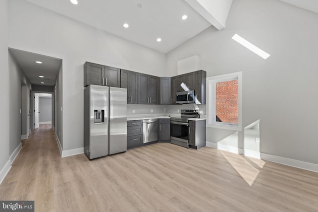 kitchen with high vaulted ceiling, light hardwood / wood-style floors, stainless steel appliances, and beam ceiling