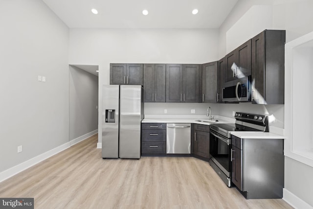 kitchen with light hardwood / wood-style flooring, stainless steel appliances, dark brown cabinetry, and sink