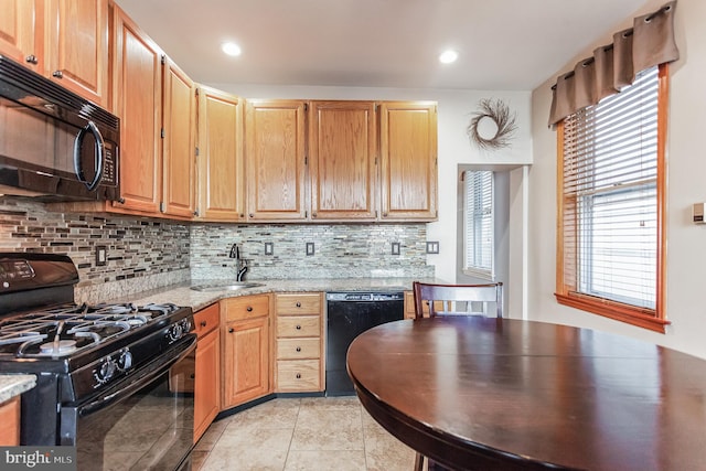 kitchen with light tile flooring, tasteful backsplash, sink, light stone countertops, and black appliances