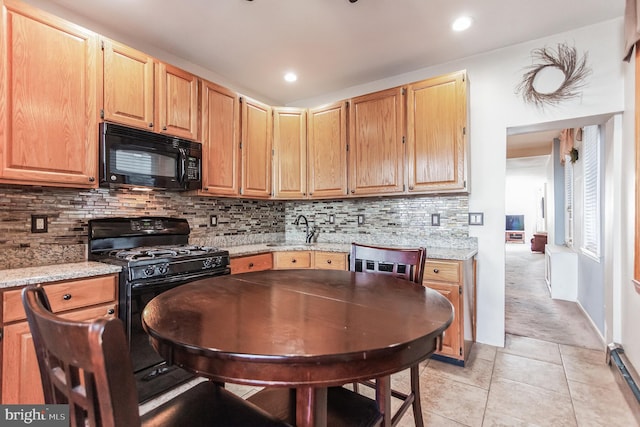 kitchen featuring light stone countertops, backsplash, sink, and black appliances