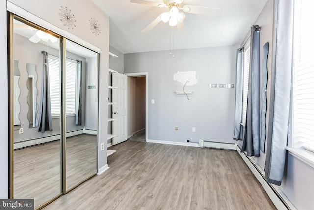 unfurnished bedroom featuring a baseboard radiator, a closet, ceiling fan, and light wood-type flooring