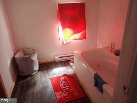 bathroom featuring hardwood / wood-style floors, a tub, and a baseboard radiator