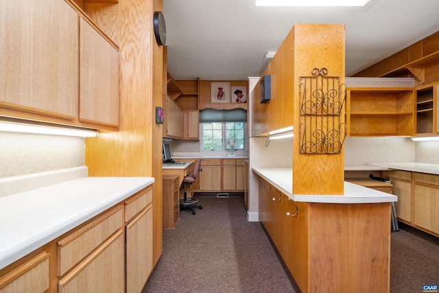 kitchen featuring light brown cabinetry, dark carpet, and built in desk