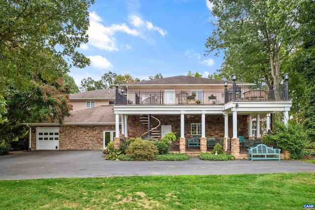 view of front facade with a balcony, a front yard, and a garage