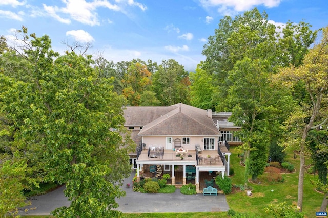 rear view of house featuring a wooden deck and a patio area