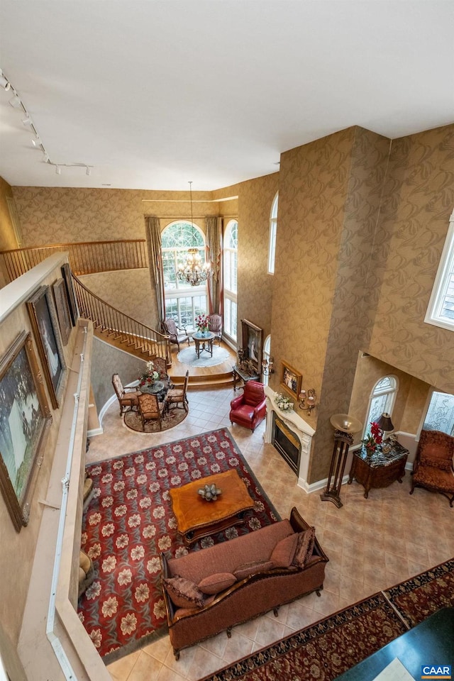 living room featuring a high ceiling, track lighting, a chandelier, and light tile flooring