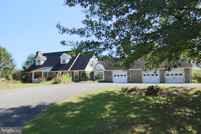 cape cod home with a front yard and a garage