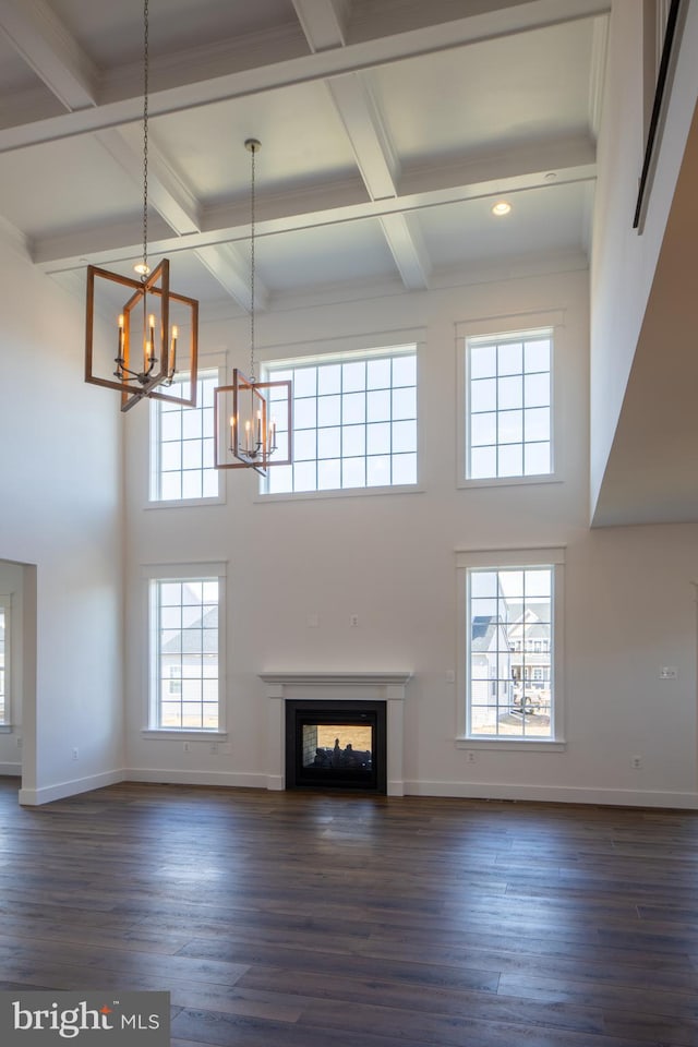 unfurnished living room with beamed ceiling, dark hardwood / wood-style floors, and a multi sided fireplace