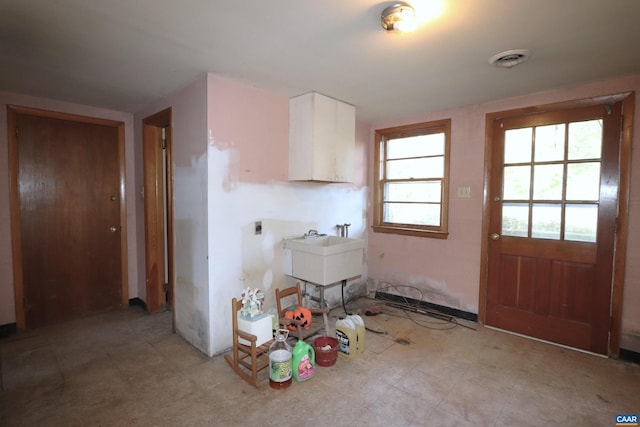 clothes washing area with electric dryer hookup, sink, and cabinets