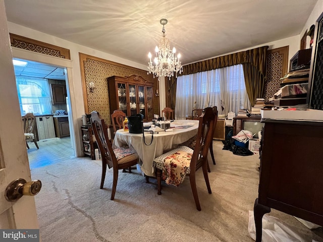 carpeted dining area with an inviting chandelier