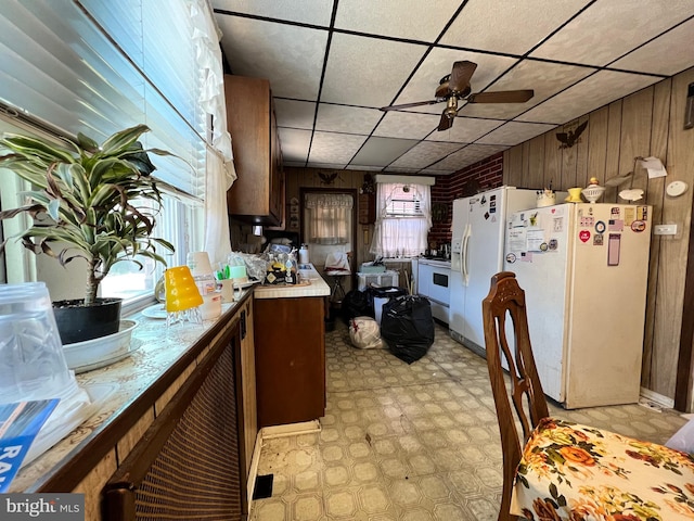 kitchen with white fridge, white fridge with ice dispenser, ceiling fan, and wooden walls