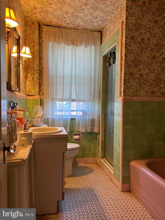 full bathroom with vanity, toilet, tile walls, and independent shower and bath