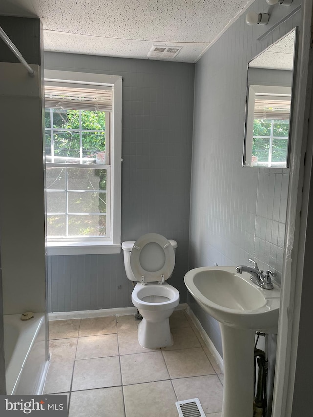 bathroom featuring a drop ceiling, toilet, and tile floors