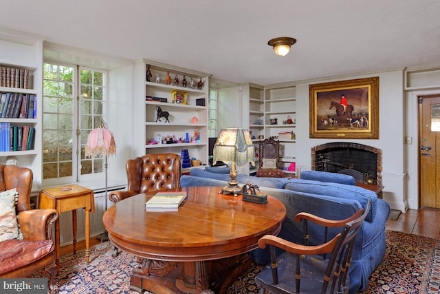 home office featuring dark hardwood / wood-style flooring, built in shelves, and a fireplace