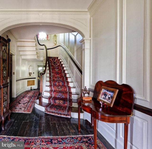 stairway featuring crown molding, ornate columns, and dark hardwood / wood-style floors