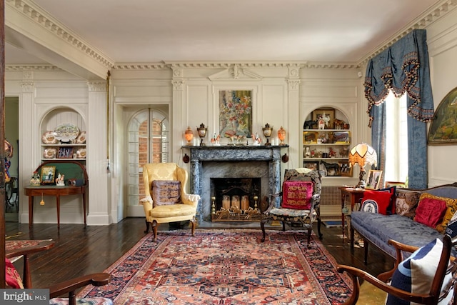 living room featuring built in features, ornamental molding, and dark hardwood / wood-style floors