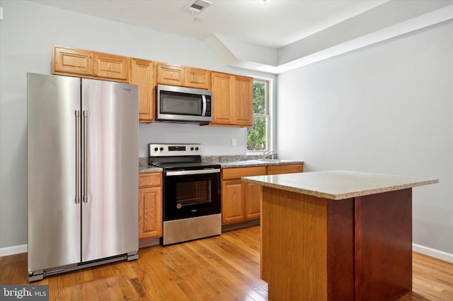 kitchen with a center island, stainless steel appliances, sink, and light wood-type flooring