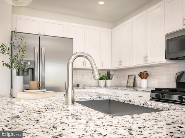 kitchen with white cabinets, appliances with stainless steel finishes, and decorative backsplash