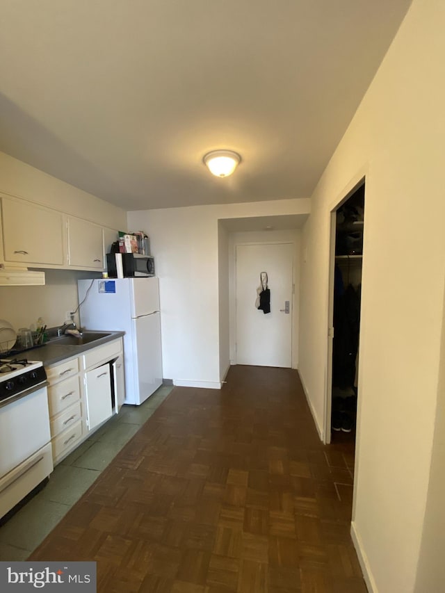 kitchen with exhaust hood, white appliances, dark parquet floors, white cabinets, and sink