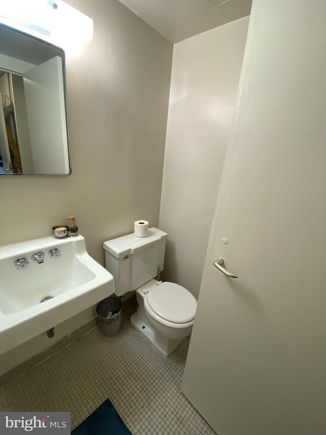 bathroom with toilet, tile patterned floors, and sink