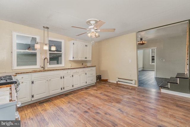 kitchen featuring white cabinetry, ceiling fan, a baseboard radiator, wood-type flooring, and sink