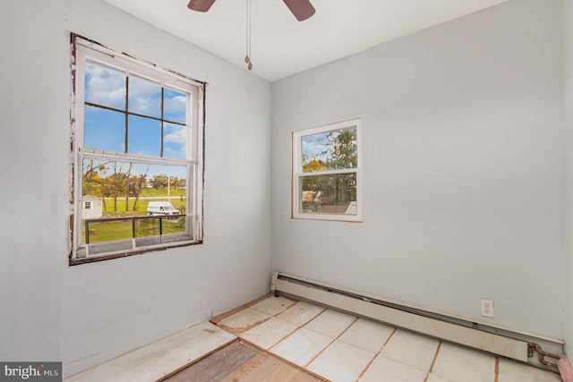 tiled empty room with ceiling fan, baseboard heating, and a healthy amount of sunlight