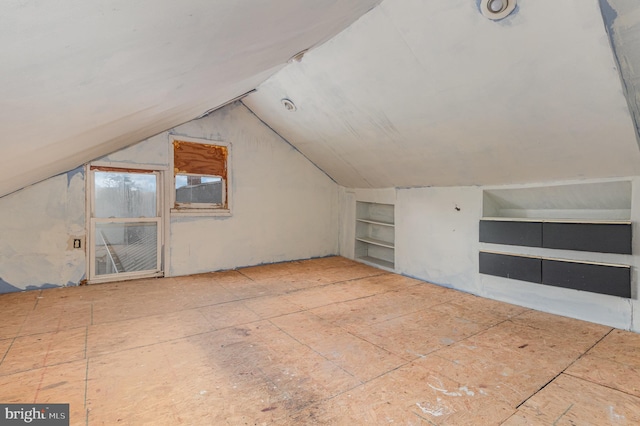 bonus room featuring built in shelves and vaulted ceiling