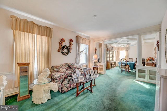 carpeted living room with ceiling fan, decorative columns, and beamed ceiling