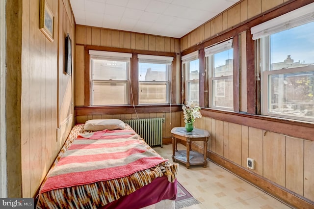 tiled bedroom featuring wood walls and radiator