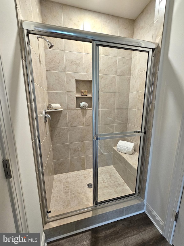 bathroom featuring wood-type flooring and an enclosed shower