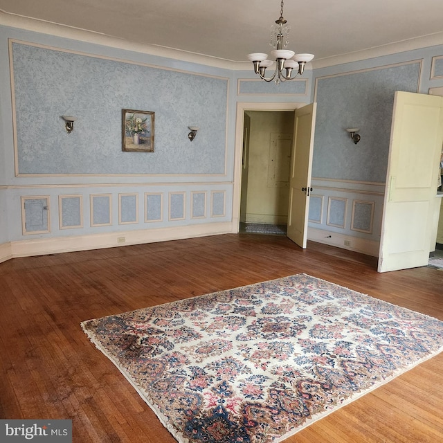 empty room with an inviting chandelier, crown molding, and dark hardwood / wood-style floors