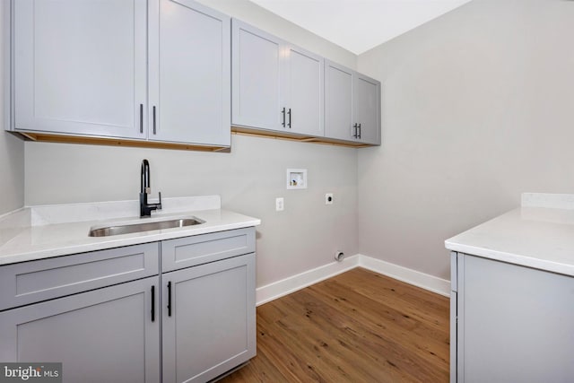 clothes washing area with sink, cabinets, hookup for a washing machine, hardwood / wood-style flooring, and hookup for an electric dryer