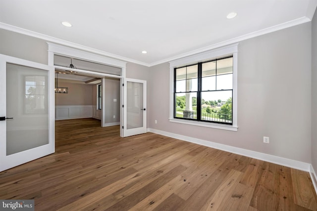 unfurnished bedroom with crown molding, an inviting chandelier, hardwood / wood-style floors, and french doors