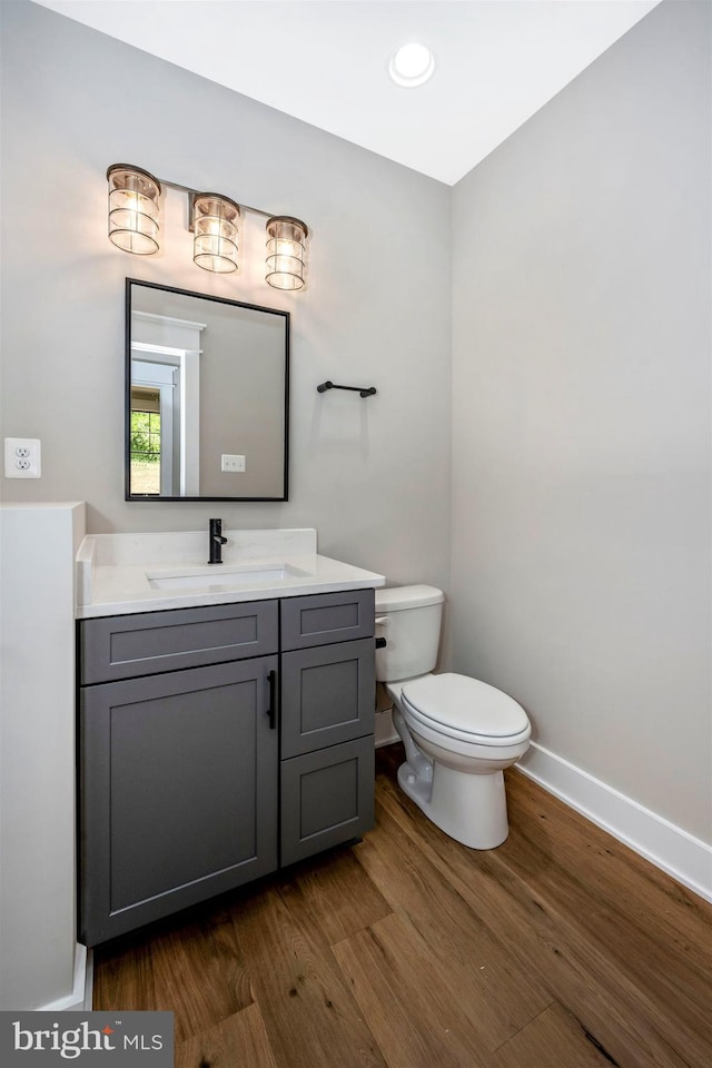 bathroom featuring wood-type flooring, vanity, and toilet