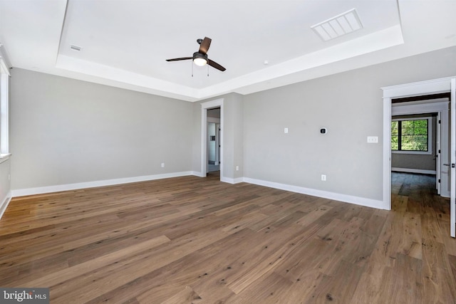 unfurnished room with dark hardwood / wood-style floors, ceiling fan, and a tray ceiling