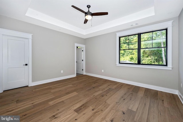 unfurnished room featuring hardwood / wood-style flooring, ceiling fan, and a raised ceiling