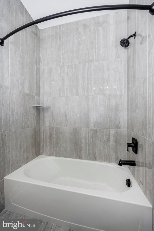 bathroom featuring tiled shower / bath combo and tile walls