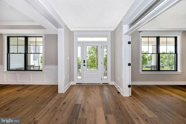 entryway with ornamental molding and hardwood / wood-style floors