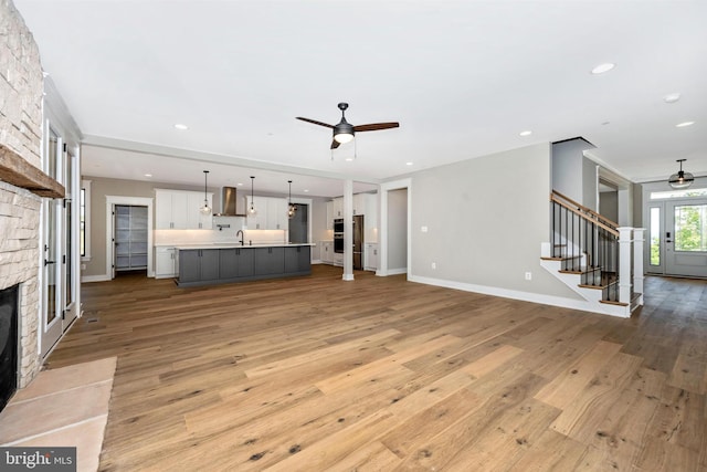 unfurnished living room featuring ceiling fan, a fireplace, and light hardwood / wood-style floors