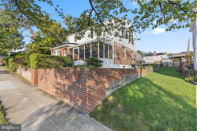 view of side of property with a sunroom and a lawn