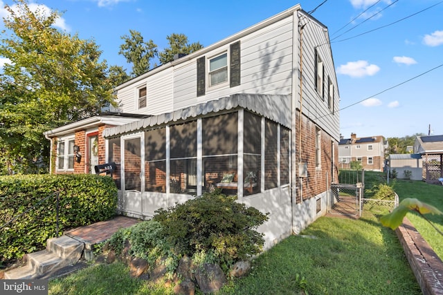 back of house featuring a sunroom and a lawn