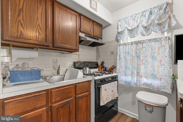 kitchen with hardwood / wood-style floors, backsplash, sink, and white range with gas cooktop