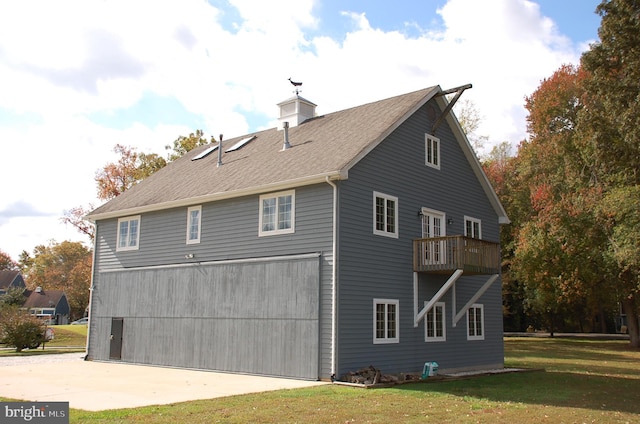 view of property exterior featuring a balcony, a yard, and a garage