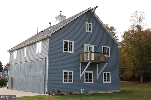 back of house with a balcony and a yard