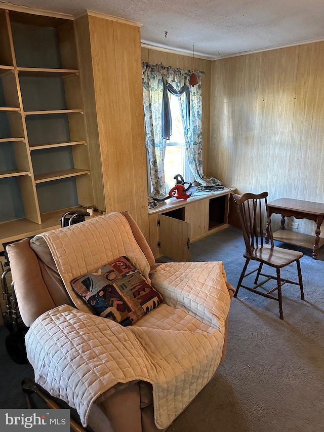 sitting room featuring ornamental molding, carpet flooring, a textured ceiling, and wood walls