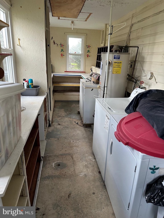 laundry room featuring water heater, laundry area, a textured wall, and washer and dryer