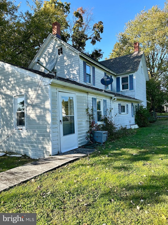 rear view of house featuring a yard and a chimney