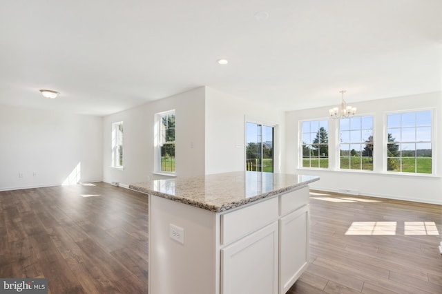 kitchen featuring a chandelier, pendant lighting, a kitchen island, hardwood / wood-style floors, and white cabinetry